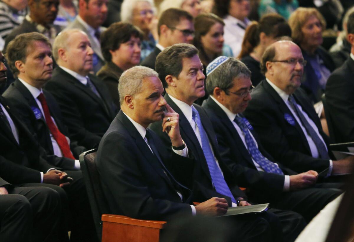 Atty. Gen. Eric H. Holder Jr., seated next to Kansas Gov. Sam Brownback, attends a service at the Jewish Community Center in Overland Park, Kan.