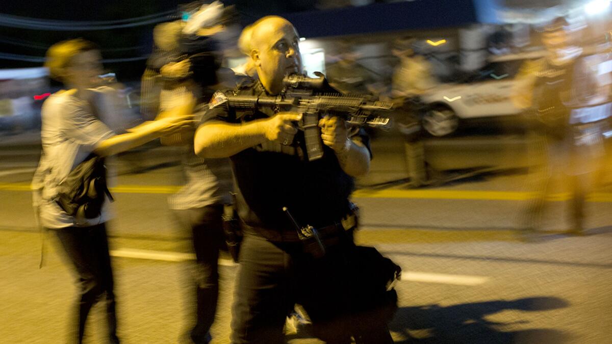 A St. Ann., Mo., police officer points an assault rifle at a demonstrator in Ferguson on Aug. 19. The officer was suspended indefinitely as a result of the incident, a St. Louis County Police Department statement said.
