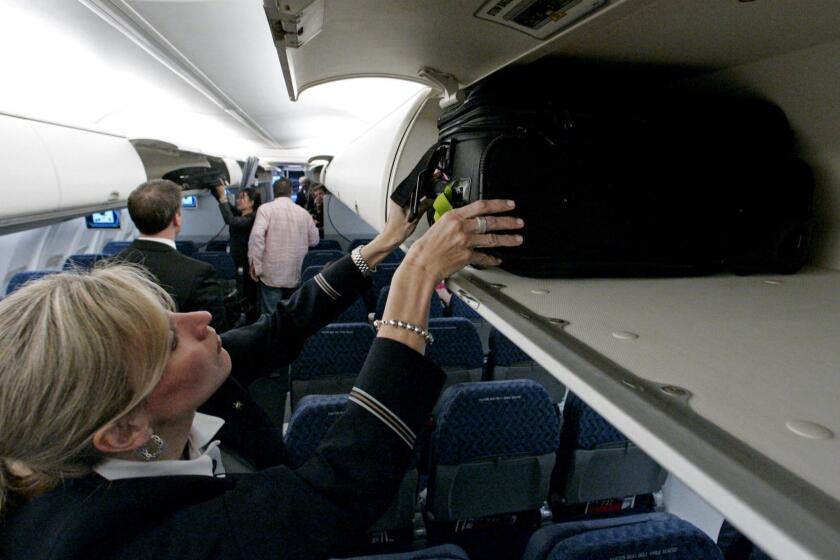 FILE - In this April 13, 2009 file photo, American Airlines flight attendant Renee Schexnaildre demonstrates the overhead baggage area during a media preview of the airline's new Boeing 737-800 jets, at Dallas Fort Worth International Airport in Grapevine, Texas. Global airlines on Tuesday, June 9, 2015 announced a new guideline that recommends shrinking carry-on bags, in an effort to free up space in packed overhead bins. (AP Photo/Donna McWilliam, File)