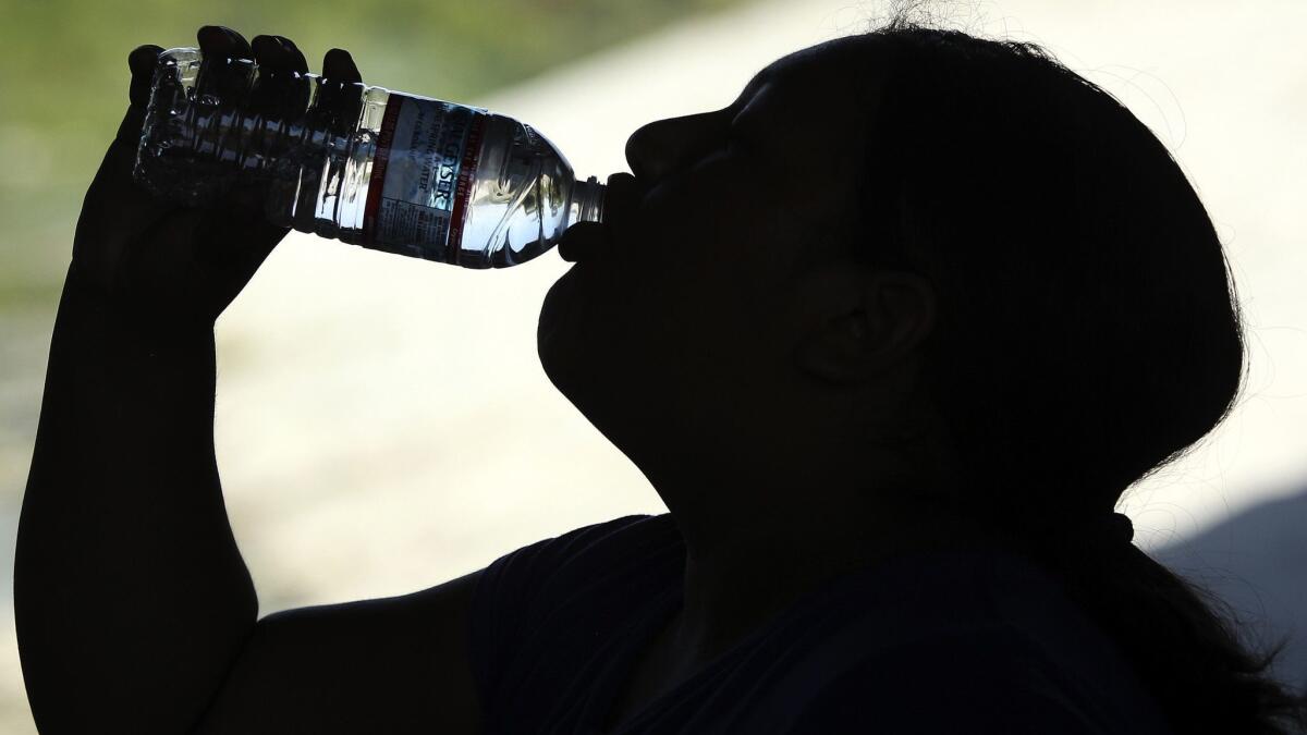 A woman gulps water to cool off during the heat wave on Saturday, July 7, 2017, in Los Angeles.