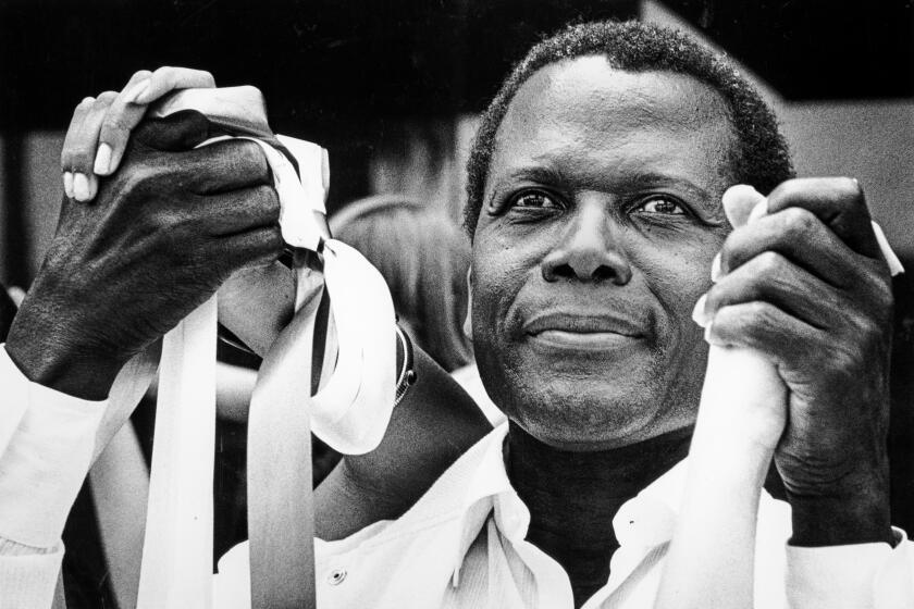 Sidney Poitier holds the hands of two individuals.