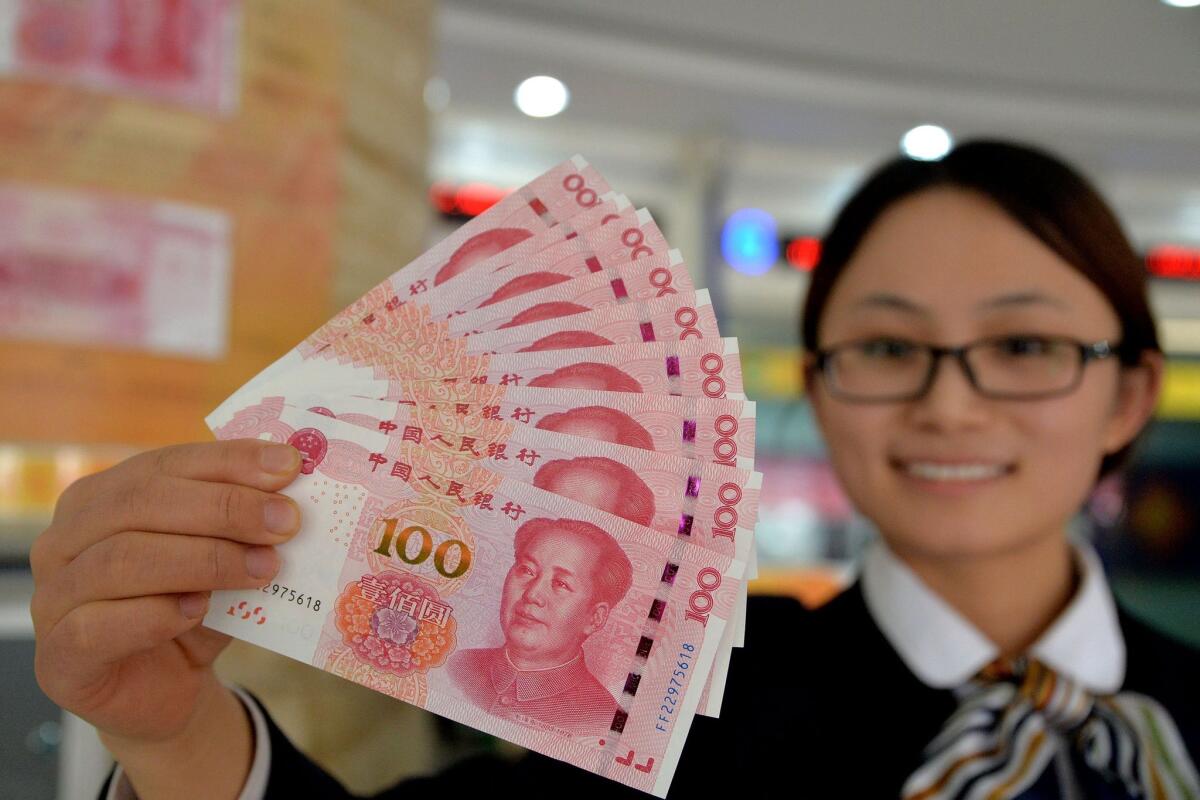 A bank employee shows new 100-yuan bank notes in Handan, in northern China's Hebei province, on Nov. 12.