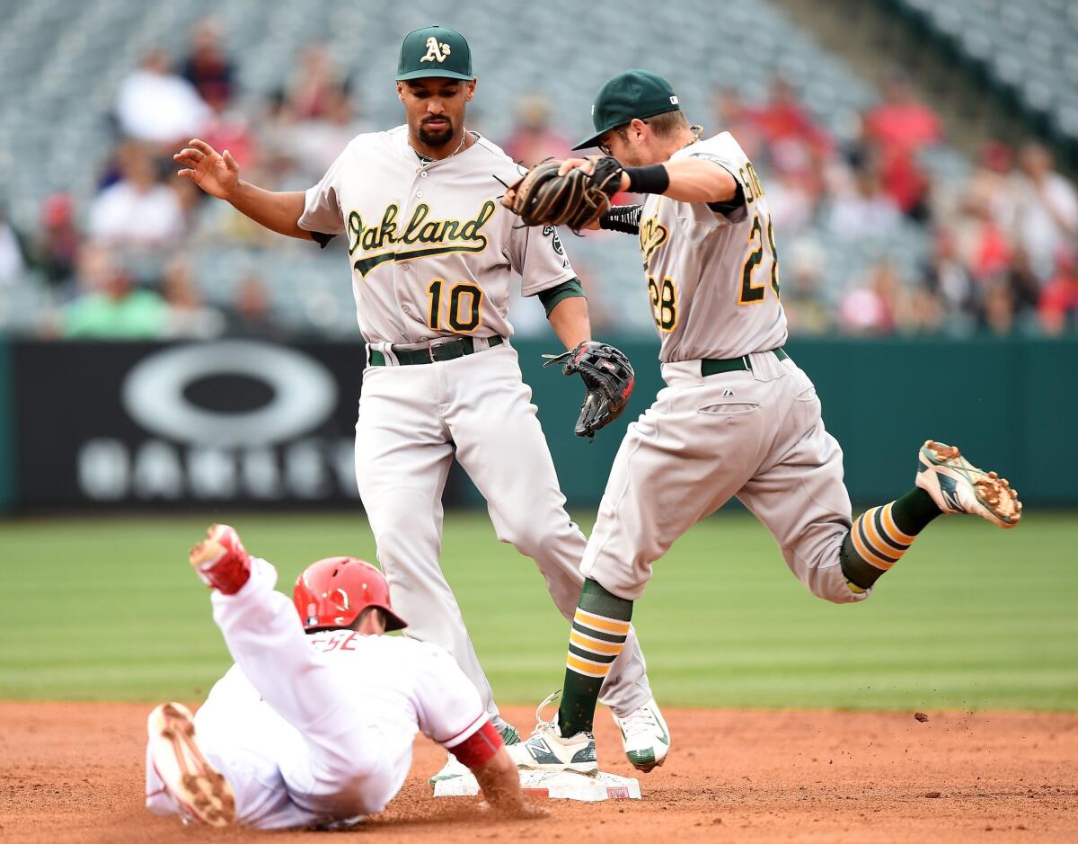 Athletics second baseman Eric Sogard races to the bag to force out the Angels' David Freese while several empty seats loom in the background.