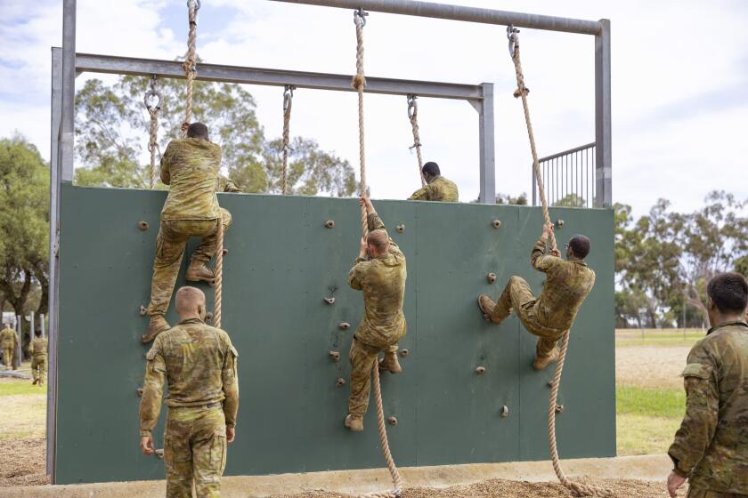 En esta imagen proporcionada por la Fuerza de Defensa de Australia, varios alumnos trepan un muro en un circuito de la Unidad de Instrucción de Reclutas en la base de la Fuerza Aérea Australiana (RAAF) en Wagga, Australia, el 23 de febrero de 2024. (Fuerza de Defensa de Australia via AP)