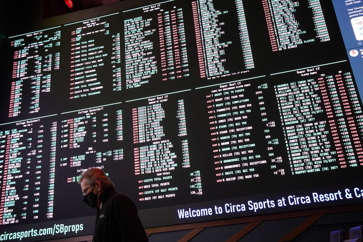 FILE- In this Feb. 3, 2021, file photo, a man walks by as betting odds for NFL football's Super Bowl 55 are displayed on monitors at the Circa resort and casino sports book in Las Vegas. Three years after the Supreme Court overturned the Professional and Amateur Sports Protection Act and allowed states to legalize sports betting, the NFL has embraced gambling as part of the landscape. (AP Photo/John Locher, File)
