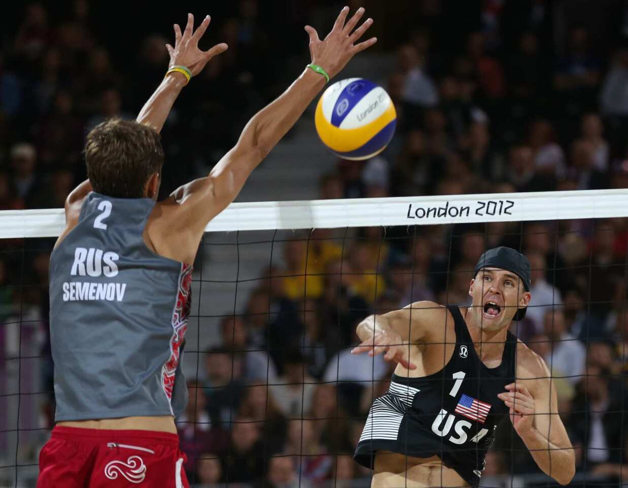 Jake Gibb, right, of the United States spikes the ball past Russia's Konstantin Semenov during the beach volleyball match.