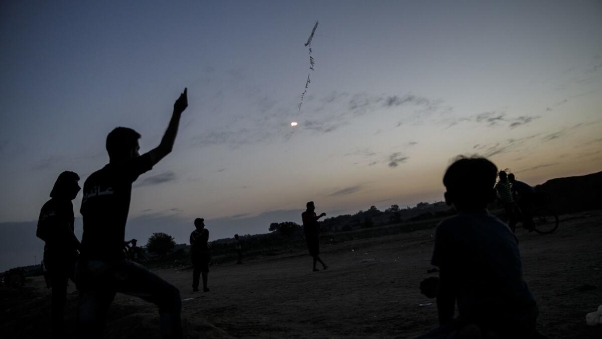 Palestinians watch a kite in the distance.