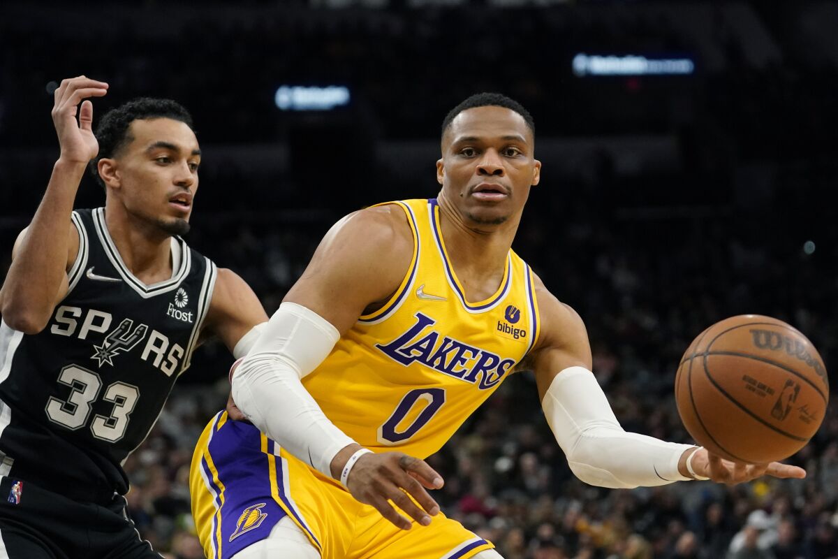 Lakers guard Russell Westbrook gathers a pass as he's defended by Spurs guard Tre Jones.