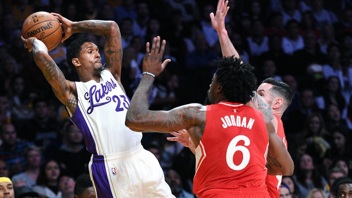 Lakers guard Lou Williams leaps to try to make a pass over Clippers center DeAndre Jordan and guard J.J. Redick.