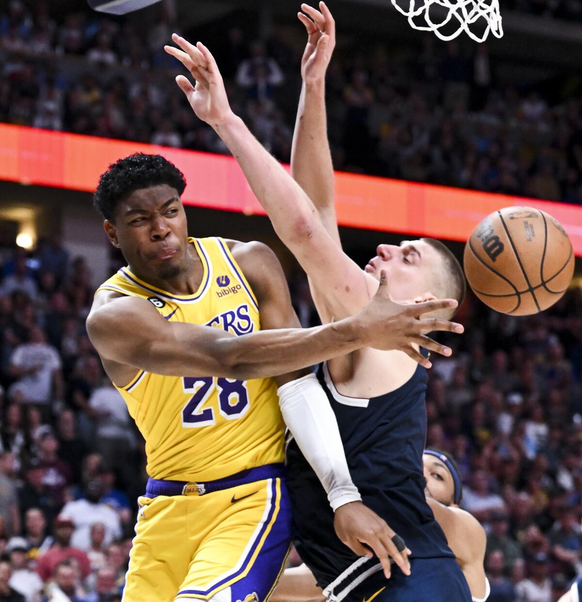 Lakers forward Rui Hachimura passes the ball around Nuggets center Nikola Jokic on a drive to the basket.