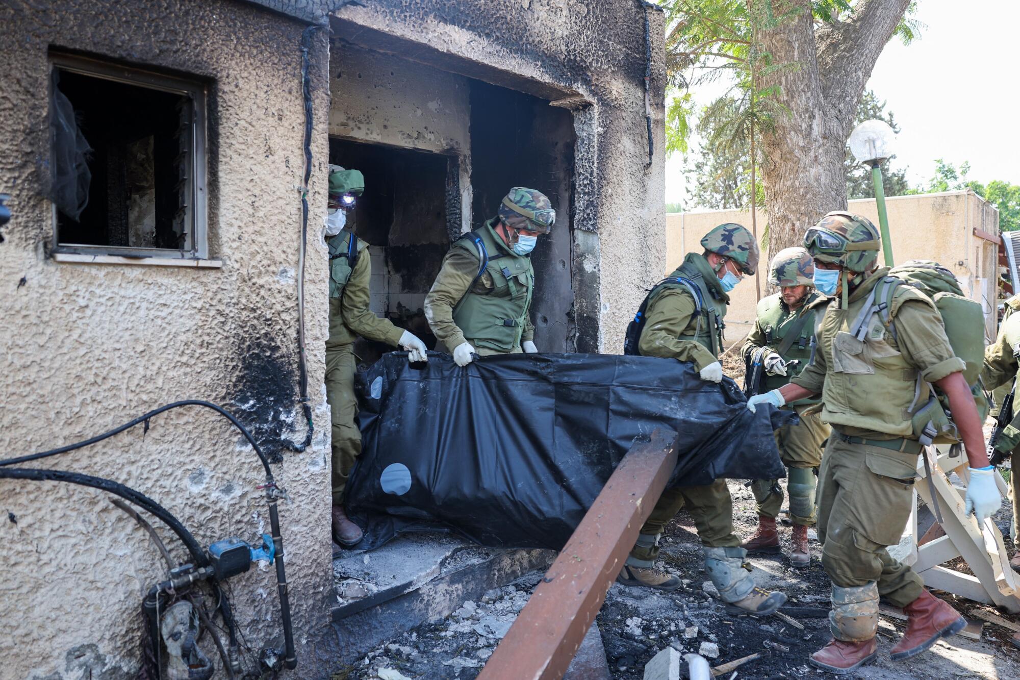 Israeli soldiers remove the body of a compatriot from a building.