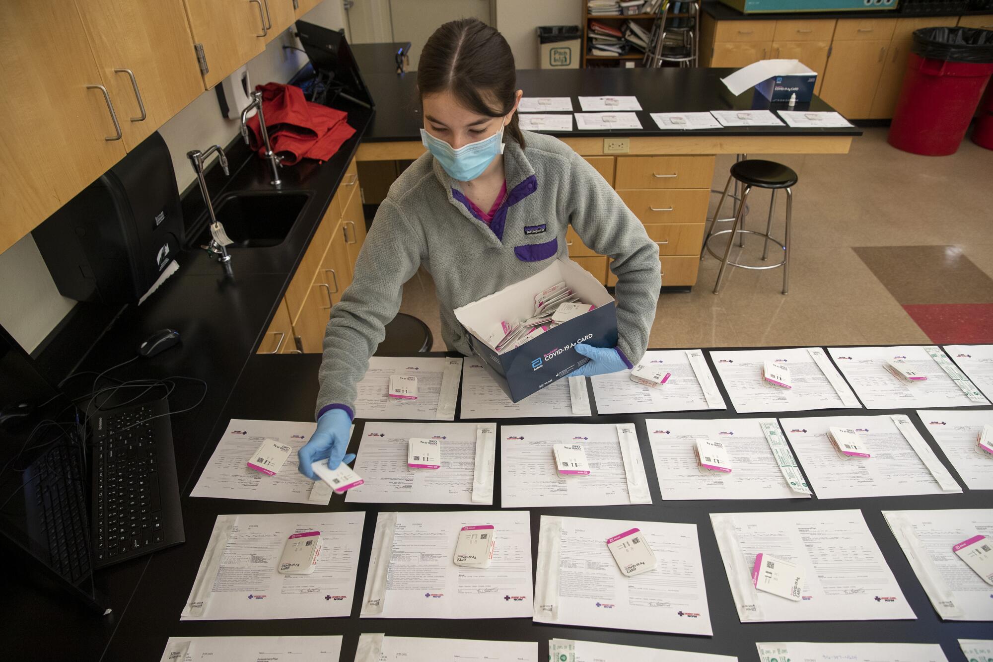 A COVID-19 testing technician sets out test cards on a countertop.