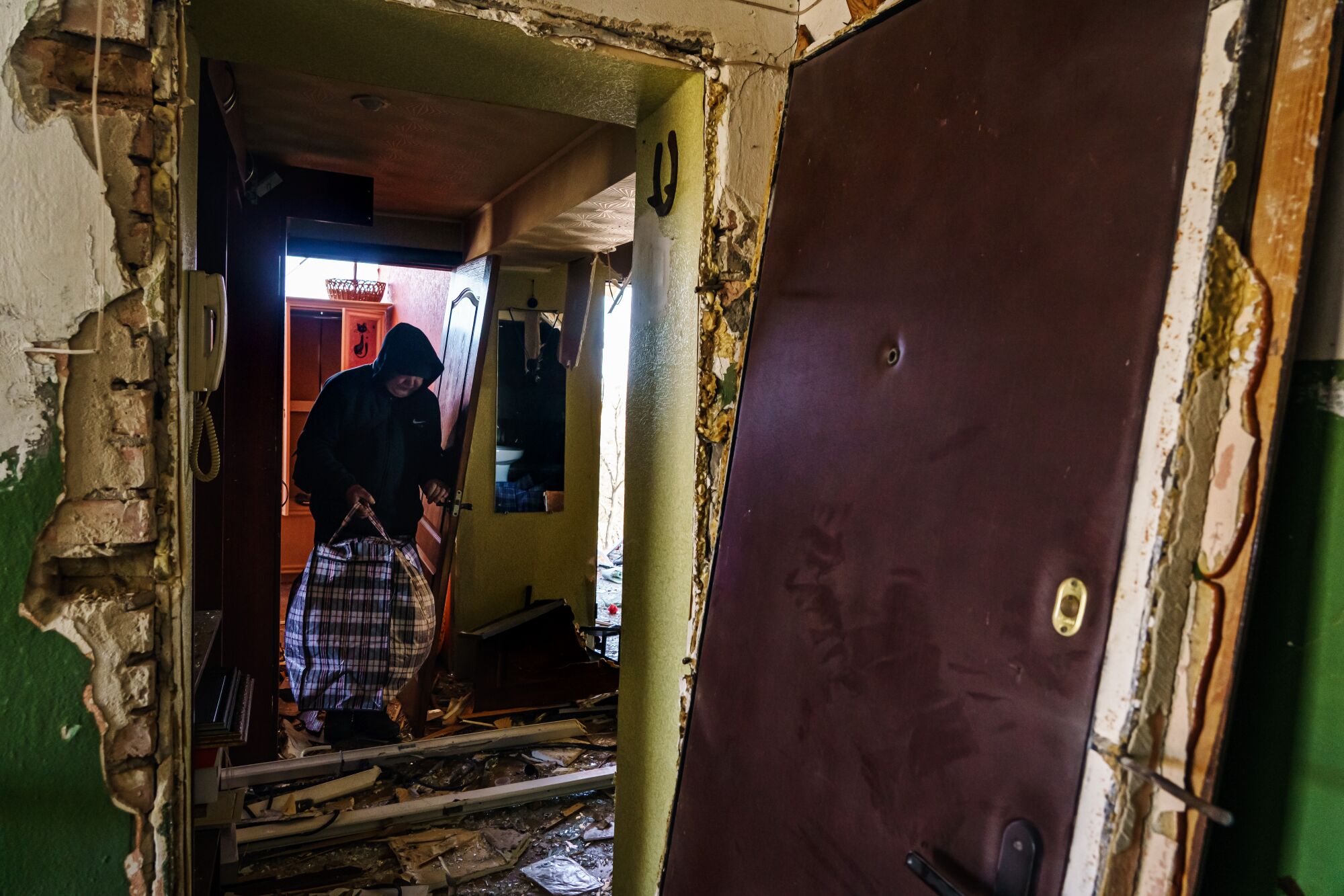 Los residentes rescatan las pertenencias de una casa que fue dañada por un ataque de misiles rusos en Kiev, Ucrania.