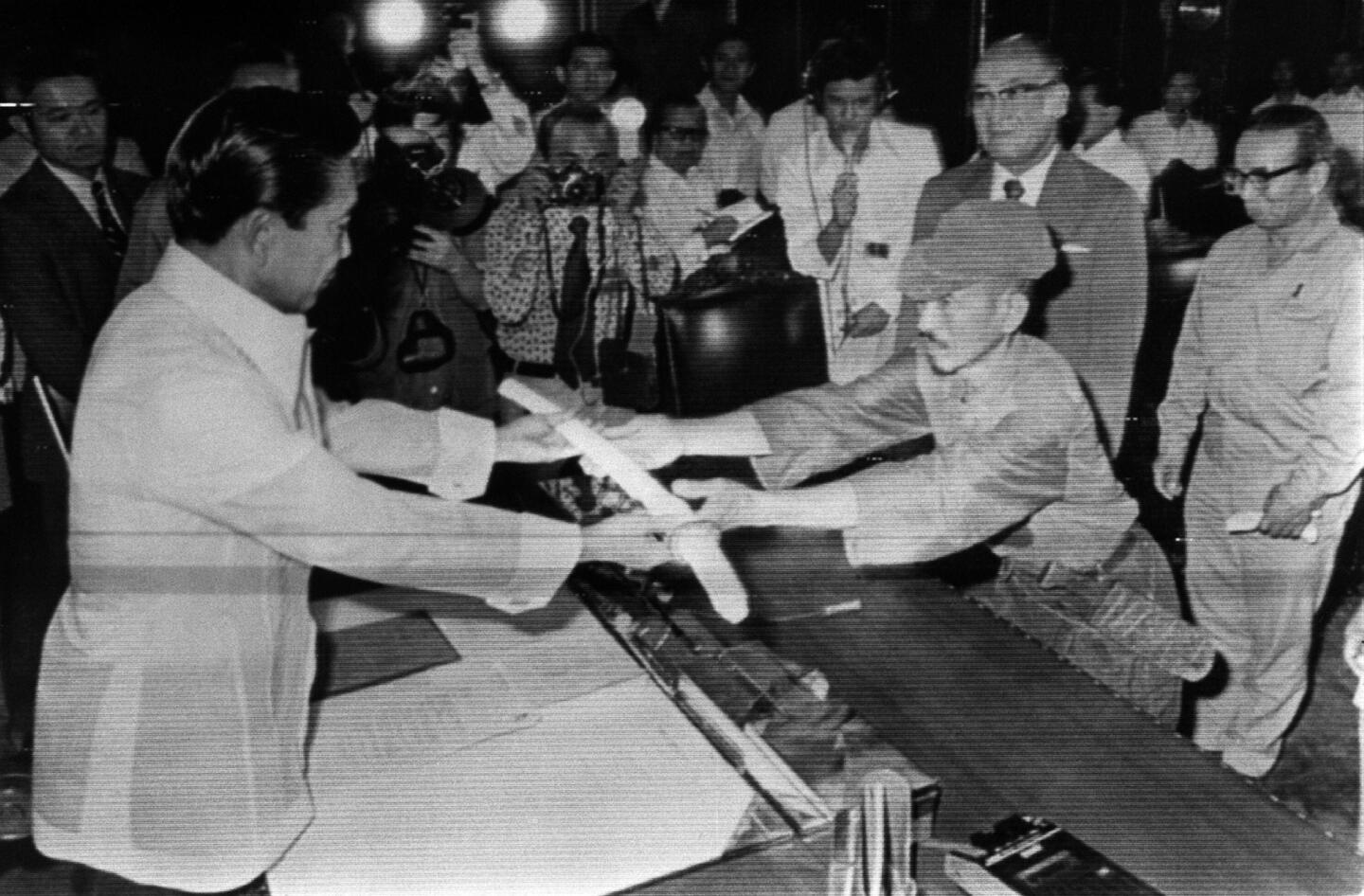 On March 11, 1974, former Japanese imperial army soldier Hiroo Onoda, right, offered his military sword to Philippine President Ferdinand Marcos, left, in surrender at the Malacanan Palace in Manila.
