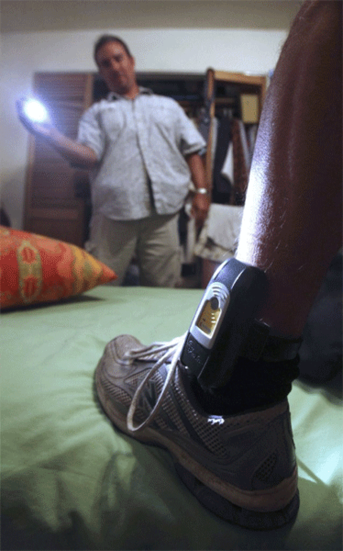 Parole Agent Steve Nakamura, shown in 2009, uses a flashlight to inspect a GPS locator worn on the ankle of a sex-offender parolee in Rio Linda, Calif.