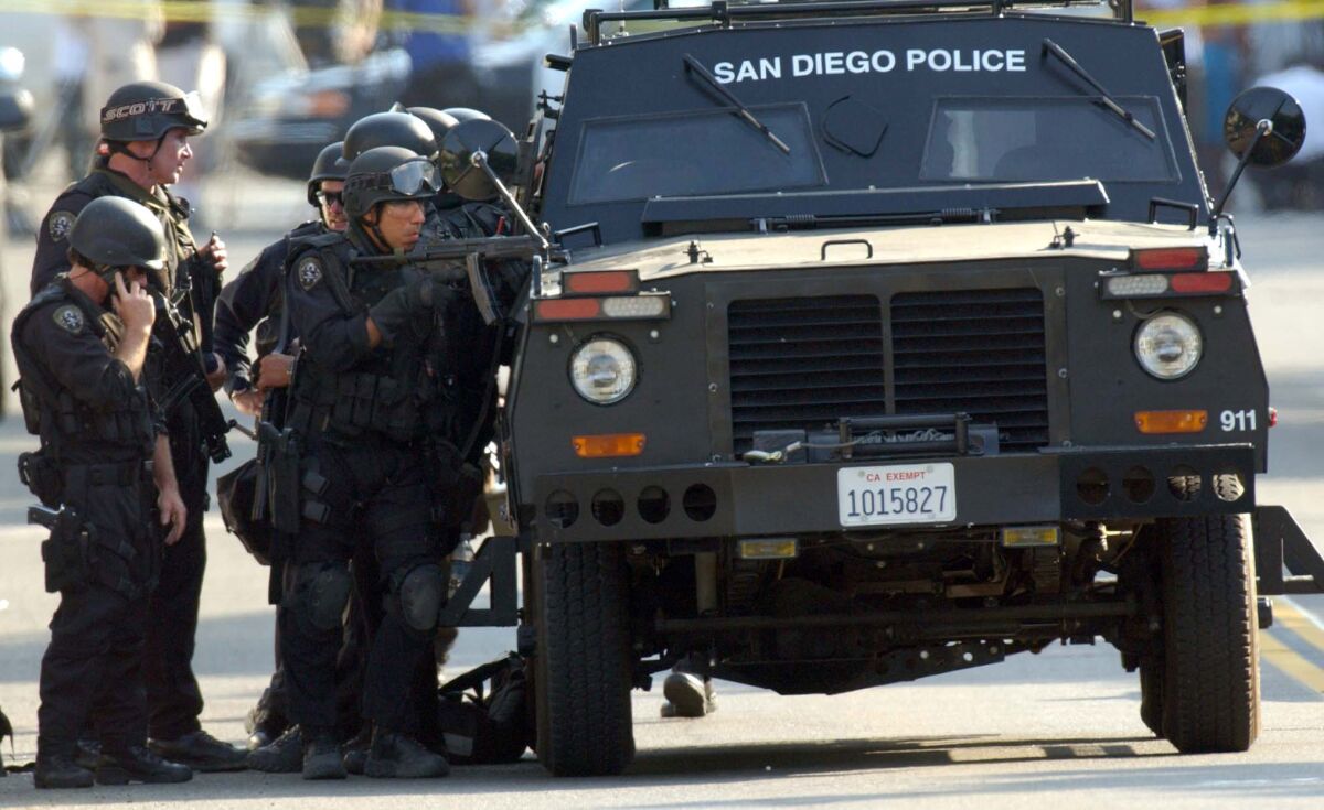 San Diego police officers use their special tactical vehicle as cover.
