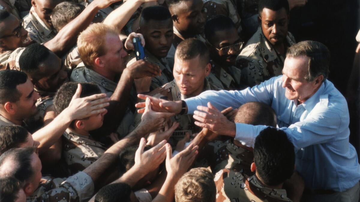 President George H.W. Bush shakes hands with a crowd of soldiers stationed in Saudi Arabia during Operation Desert Shield on Nov. 22, 1990.