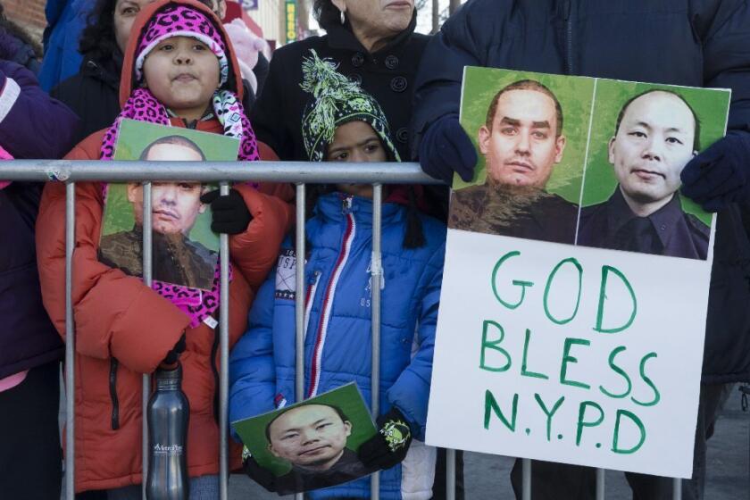 Mourners at NYPD Officer Rafael Ramos' funeral hold photos of Ramos and Officer Wenjian Liu.