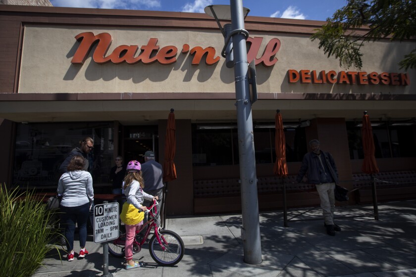 Patrons wait to pick up their food outside Nate 'n Al's on Sunday.