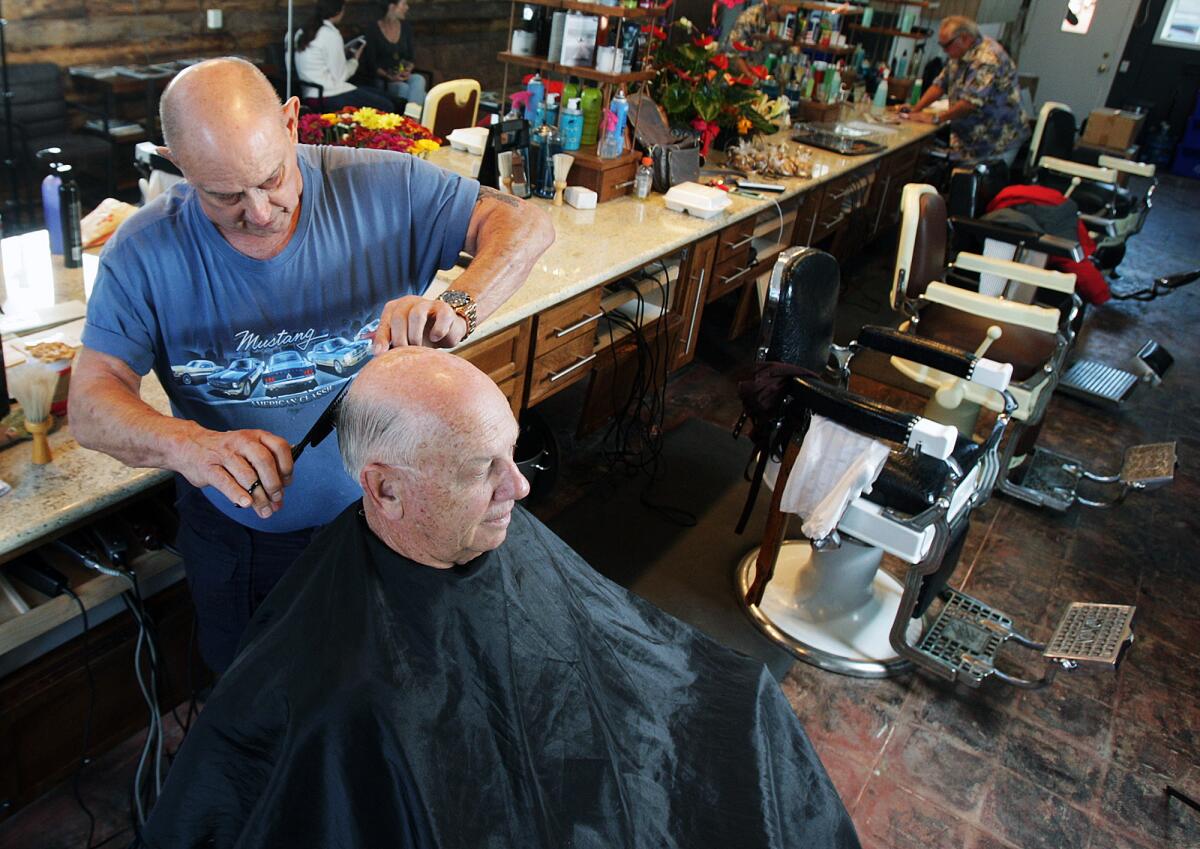 Tom Hokinson, 73, of La Cañada, who has been coming for a haircut for 45 years, gets a trim from 47-year barber Jack Roscher, at the Montrose Barber Shop on Wednesday, November 25, 2015. The barber shop has been in Montrose for 70 years, with Jack at the helm for 47. His granddaughter Lynn plans to take over the business and hopes to retire there.