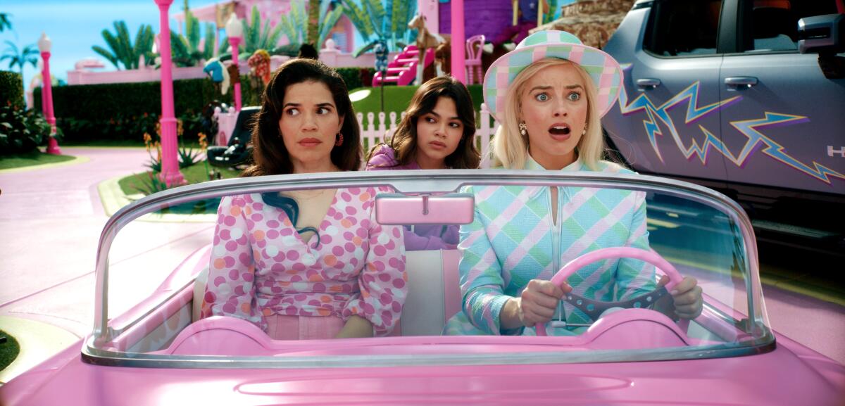 America Ferrera and Margot Robbie as Barbie drive a pink convertible car