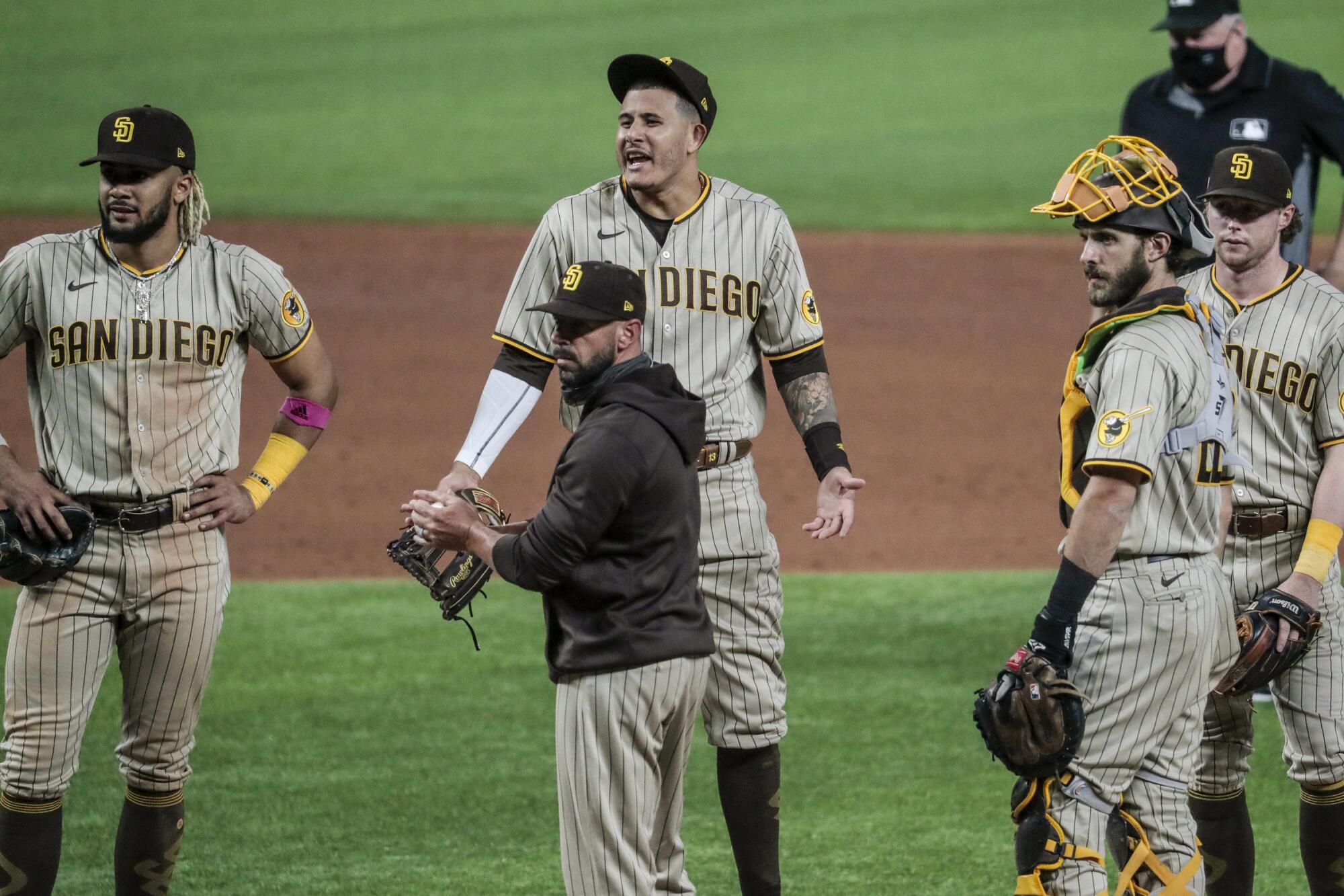 San Diego Padres players, including shortstop Manny Machado, top, complain to umpire Lance Barrett.