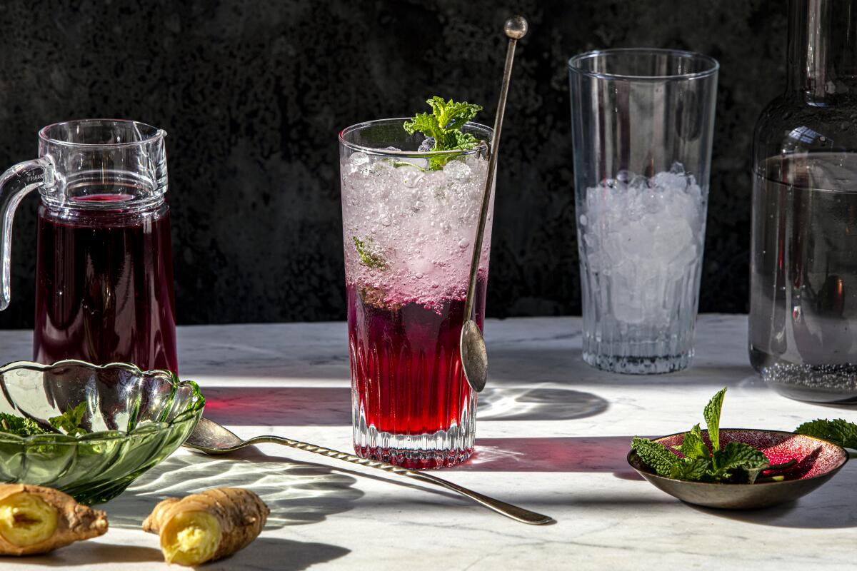 A tall, clear glass filled with a red drink and crushed ice.