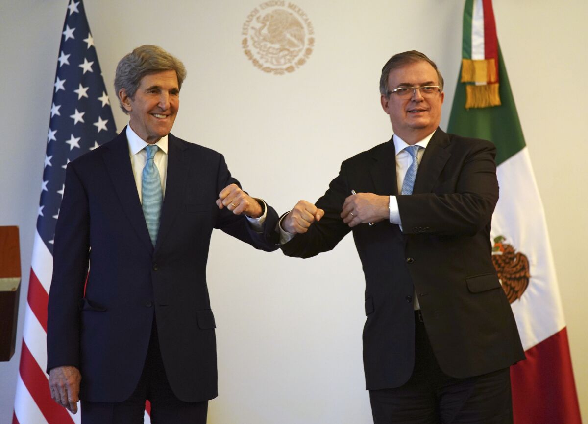 U.S. climate envoy John Kerry, left, bumps elbows with Mexican Foreign Minister Marcelo Ebrard during a photo opportunity on the sidelines of a meeting in Mexico City, Wednesday, Feb. 9, 2022. Kerry arrived for talks amid high tensions over Mexico’s plan to favor its state-owned electricity company and limit private and foreign firms that have invested in renewable energy. (AP Photo/Fernando Llano)