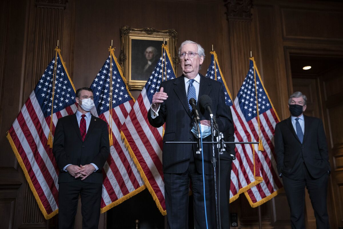 Senate Majority Leader Mitch McConnell speaks in front of a display of U.S. flags