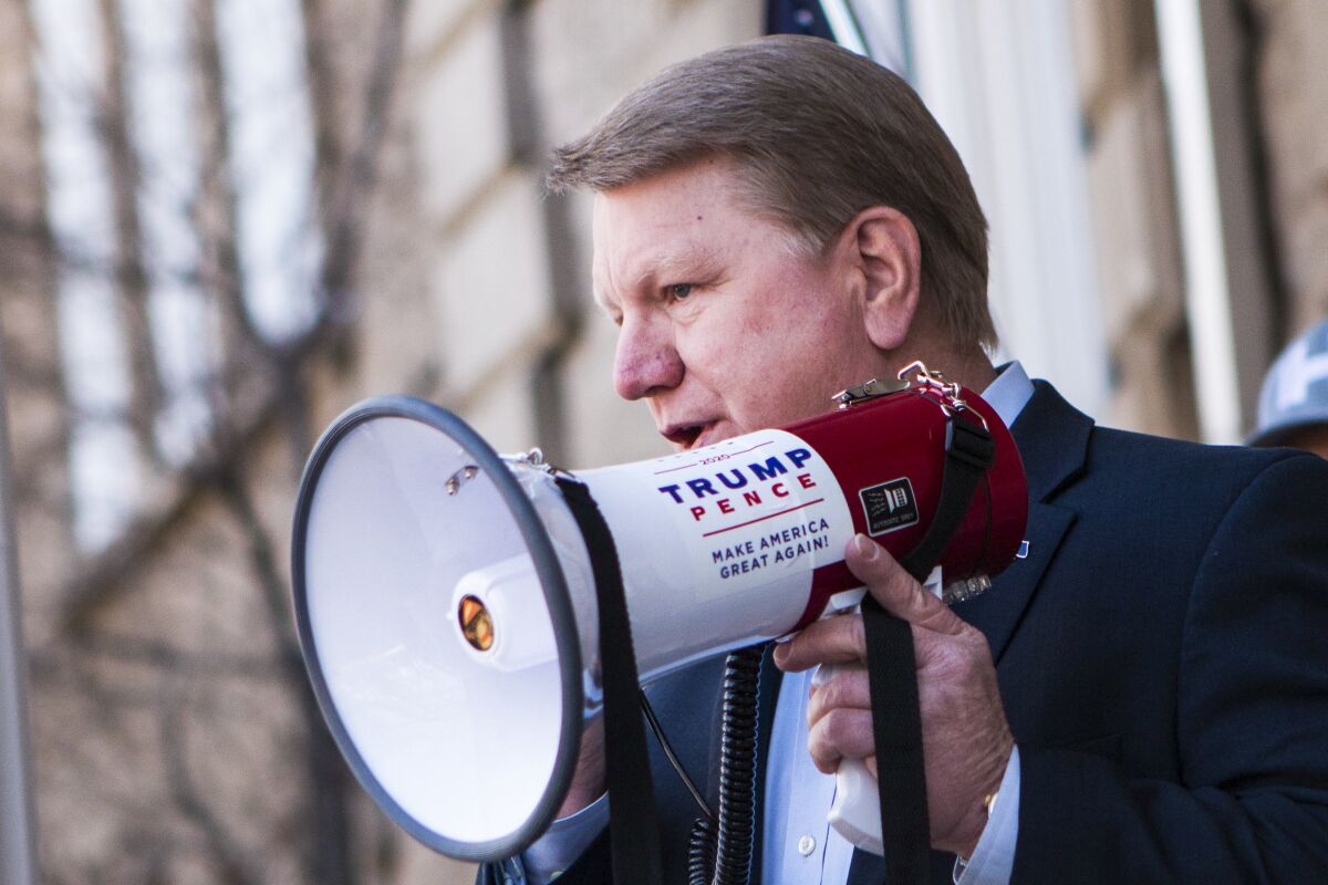 A man holds a bullhorn while speaking outdoors
