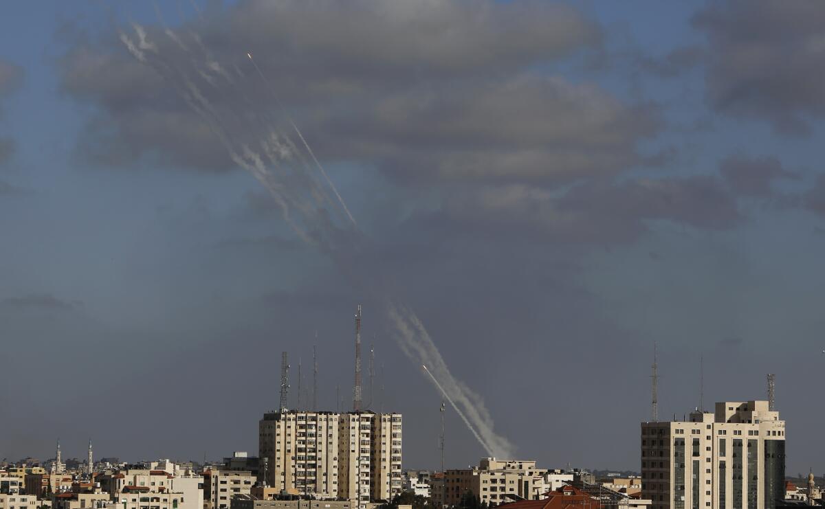 Rockets streak into the sky above a line of buildings.