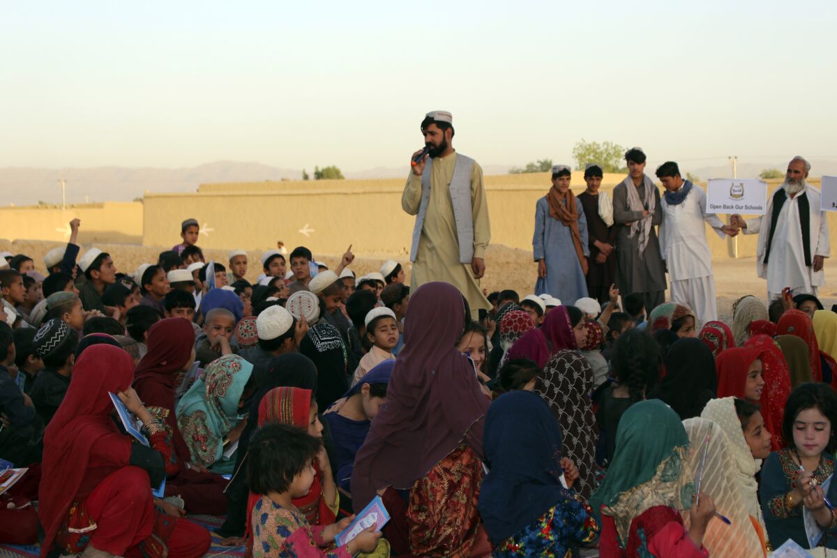 Matiullah Wesa, a girls' education advocate, reads to students in the open area in Spin Boldak district in the southern Kandahar province of Afghanistan on May 21, 2022. Matiullah Wesa, founder and president of Pen Path — a local nongovernmental group that travels across Afghanistan with a mobile school and library — was arrested in the Afghan capital on Monday, March 27, 2023. (AP Photo/Siddiqullah Khan)