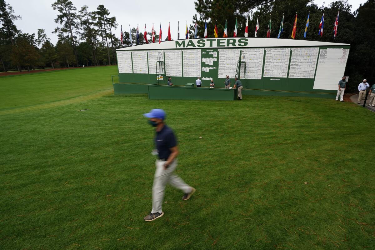 A man wearing a face mask because of the coronavirus outbreak walks past the scoreboard Friday.