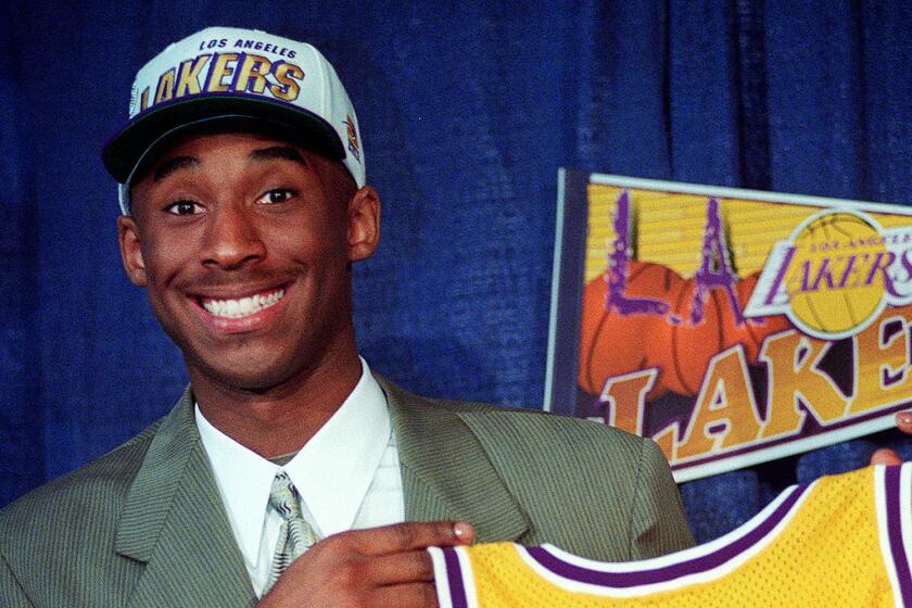 Kobe Bryant, 17, jokes with the media as he holds his Los Angeles Lakers jersey during a news conference.