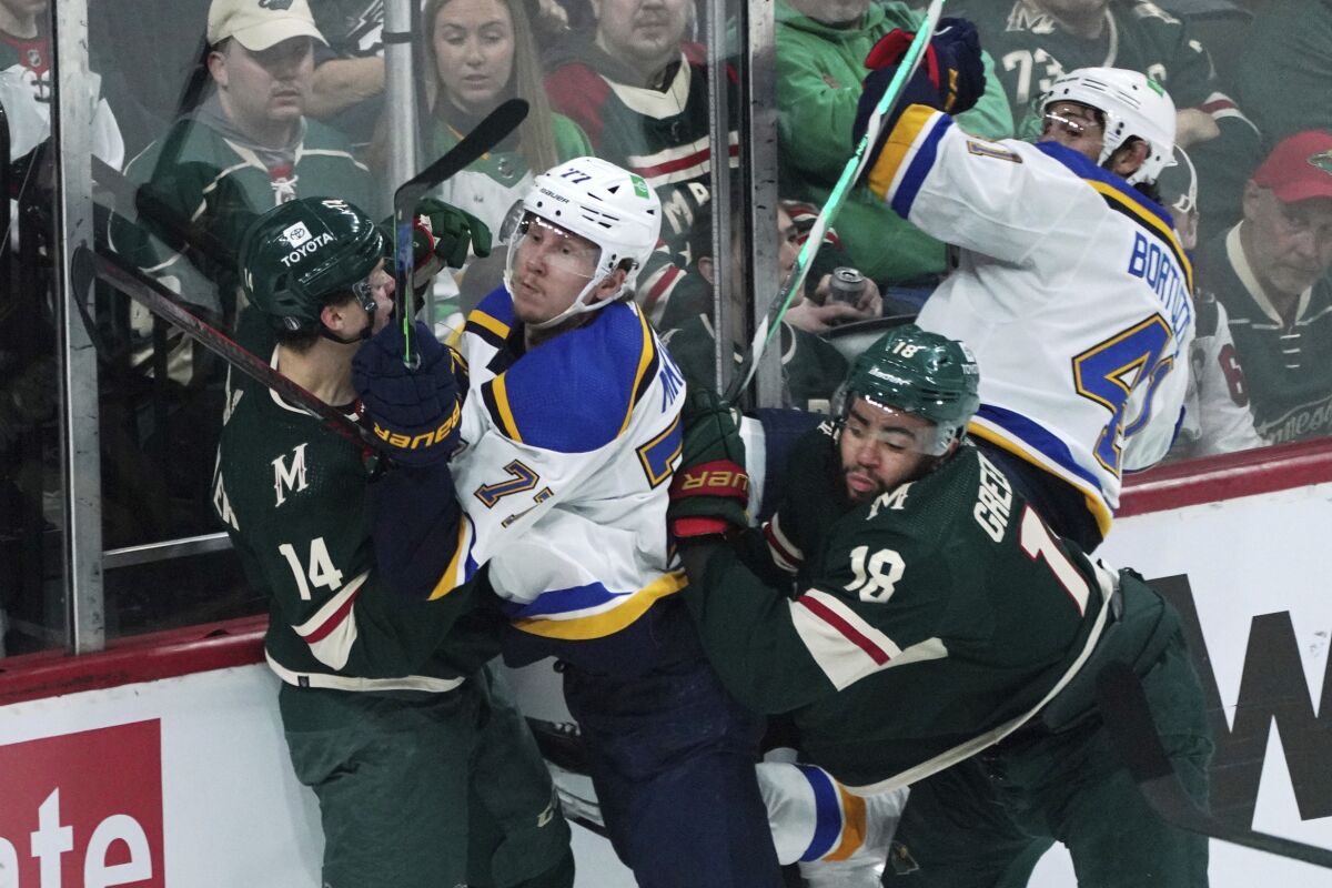 St. Louis Blues' Niko Mikkola (77) is squeezed along the boards between Minnesota Wild's Joel Eriksson Ek (14) and Jordan Greenway (18) in the first period of Game 1 of an NHL hockey Stanley Cup first-round playoff series, Monday, May 2, 2022, in St. Paul, Minn. (AP Photo/Jim Mone)