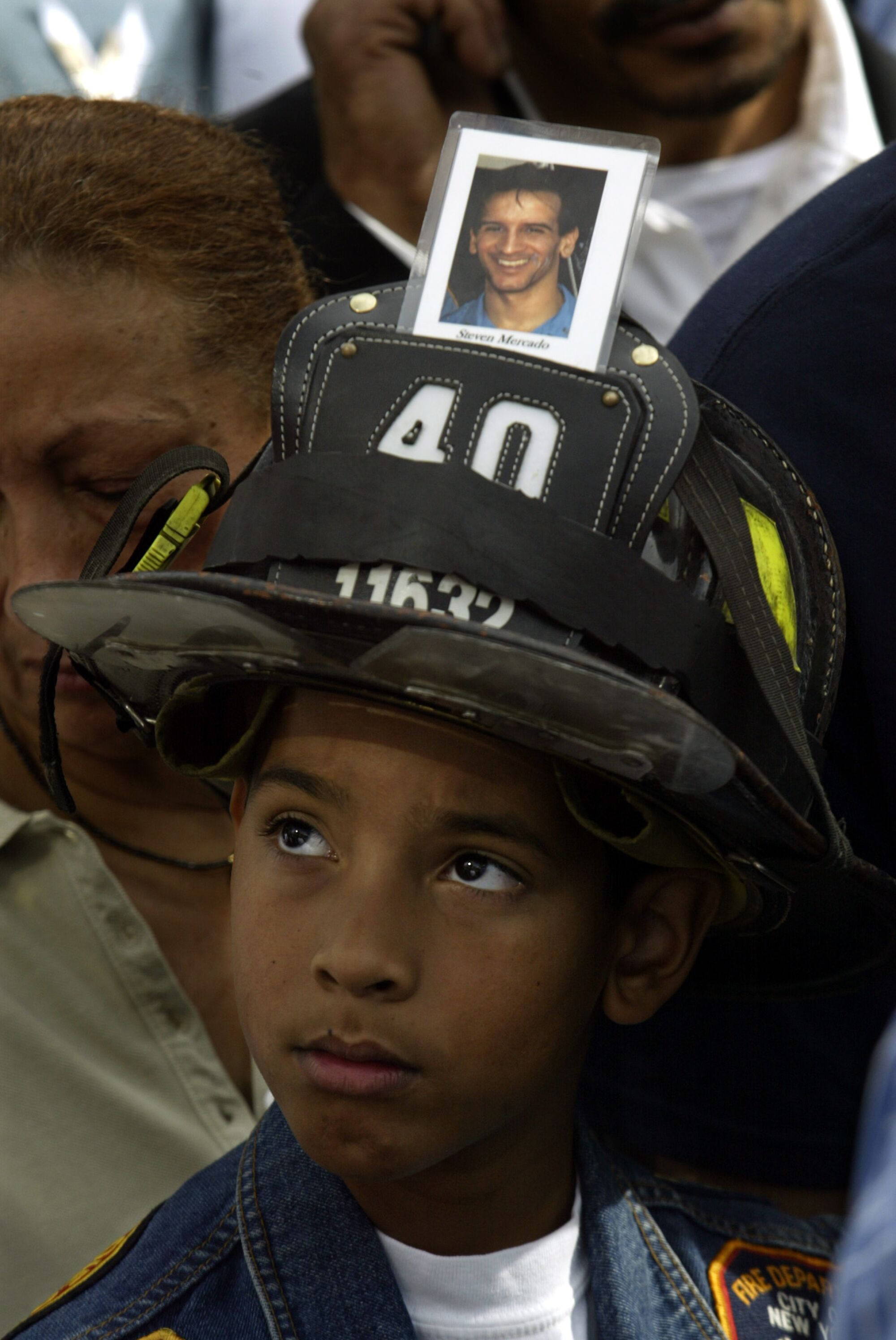 A boy wears a firefighter's helmet with a photo attached