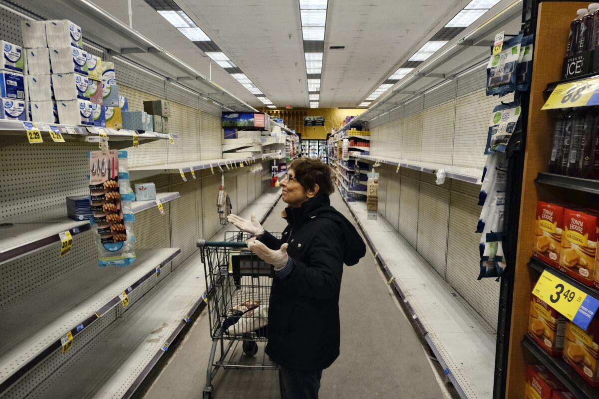 A gloved grocery shopper expresses dismay over the empty shelves at a Ralphs supermarket in Panorama City on Friday.