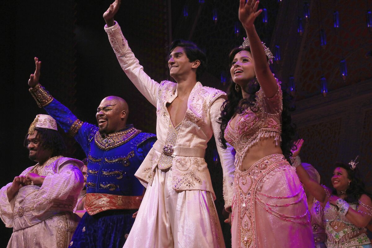 This image released by Disney Theatrical Productions shows, from second left, Michael James Scott as Genie, Michael Maliakel as Aladdin, and Shoba Narayan as Jasmine after a performance of the Broadway musical "Aladdin" in New York on Sept. 28, 2021. (Curtis Brown/Disney Theatrical Productions via AP)