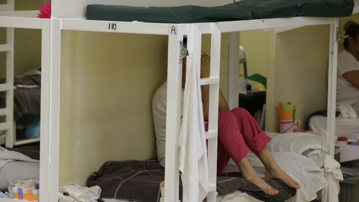 A detainee in 2017 sits on a bunk in a women's area at the Northwest Detention Center in Tacoma, Wash. The center is run by Geo Group.