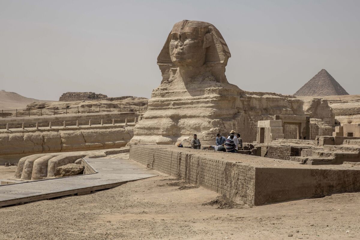 FILE - People work at the site of the Sphinx and the Giza Pyramids, in Giza, Egypt, Wednesday, March 25, 2020. The second “Field of Dreams” baseball game is Thursday night, Aug. 11, 2022, in the cornfields of eastern Iowa, near the site of the beloved 1989 movie. If Major League Baseball is looking for another place for a game, oh man, do we have some fun ideas. (AP Photo/Nariman El-Mofty, File)