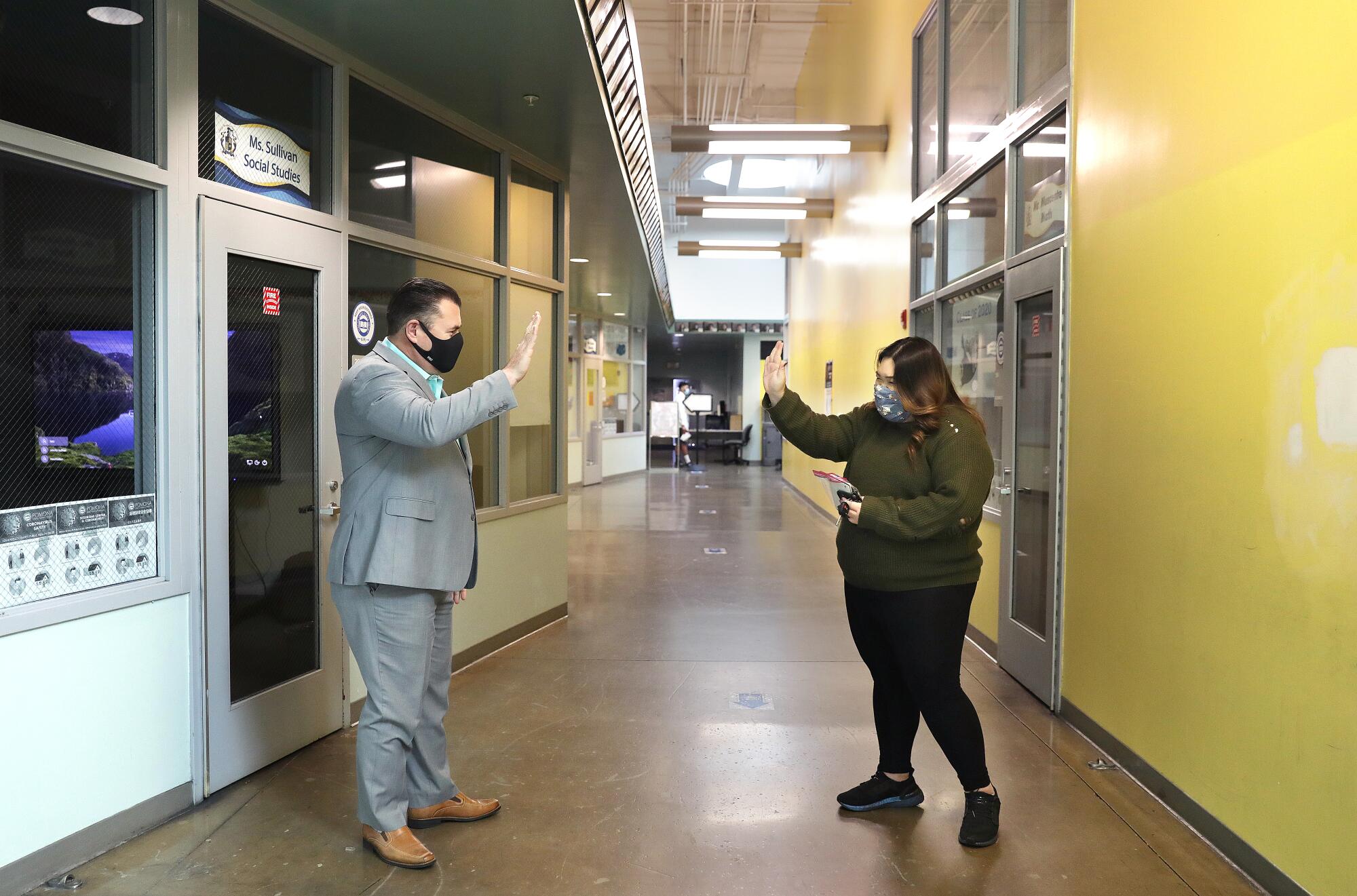 Kaitlyn Nguyen, right, "air high-fives" principal Joseph Biagioni in a school hallway