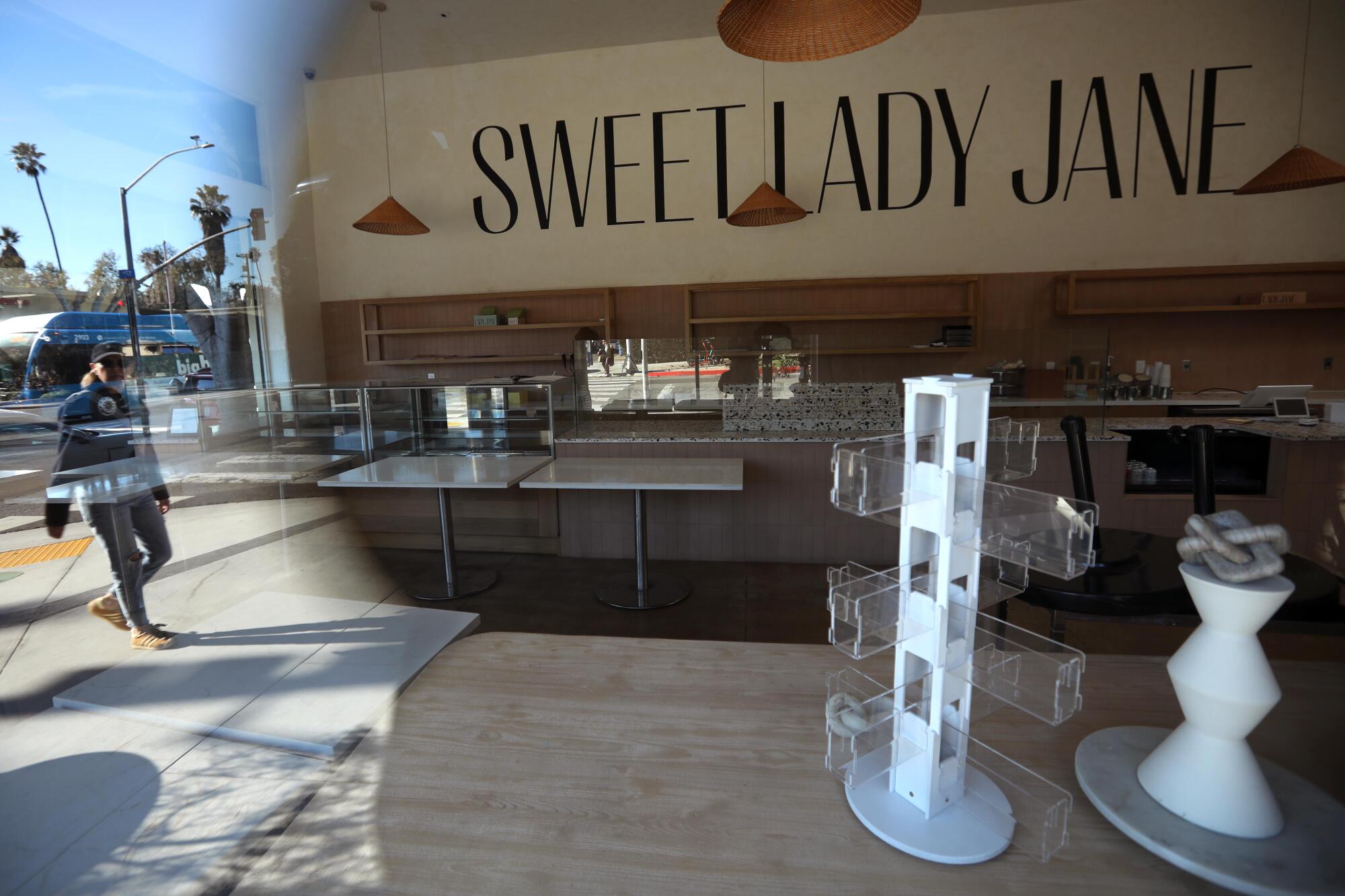 A pedestrian, reflected in the window at Sweet Lady Jane walks past the shuttered bakery in Santa Monica.