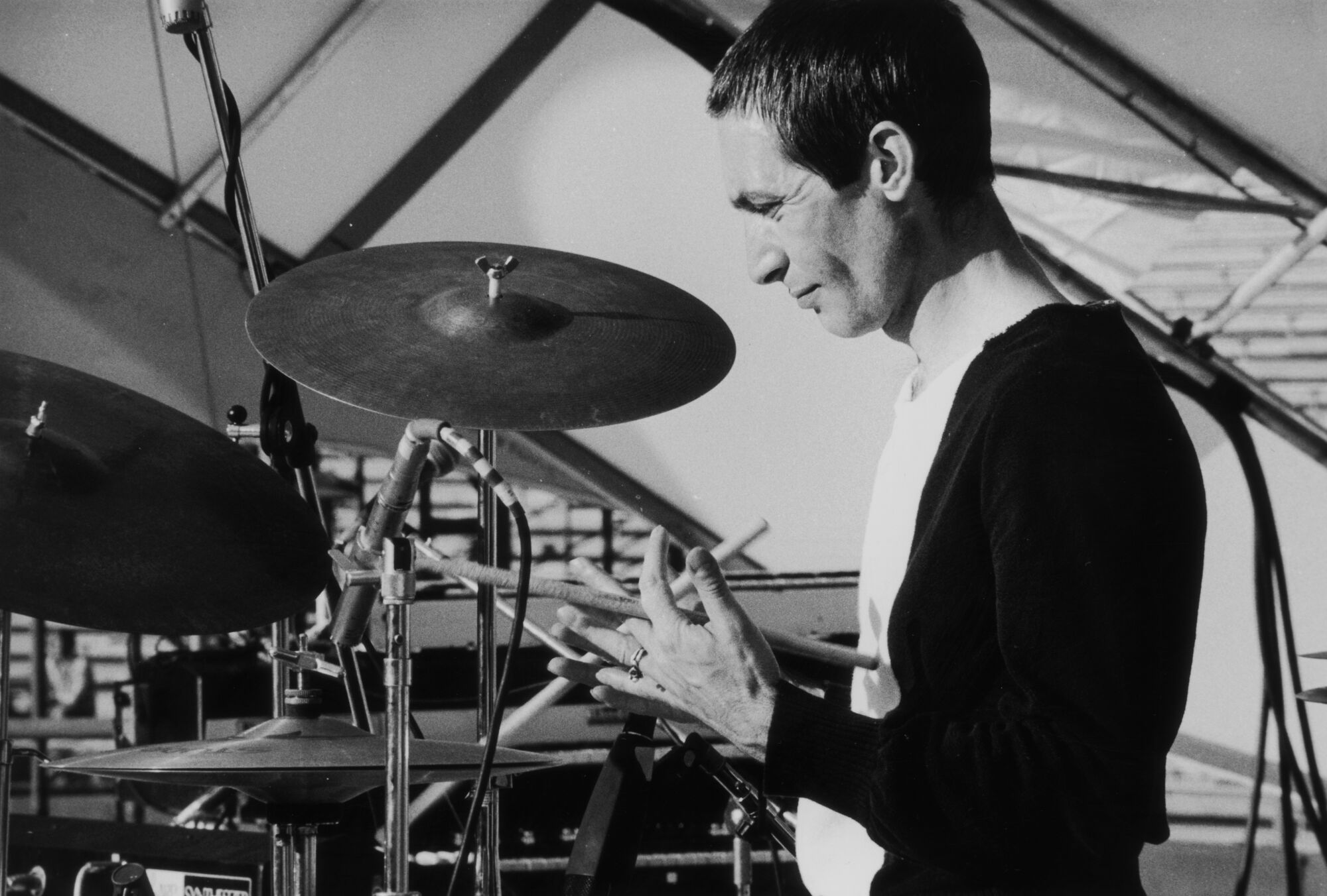 A black-and-white photo of drummer Charlie Watts at his kit in 1975.