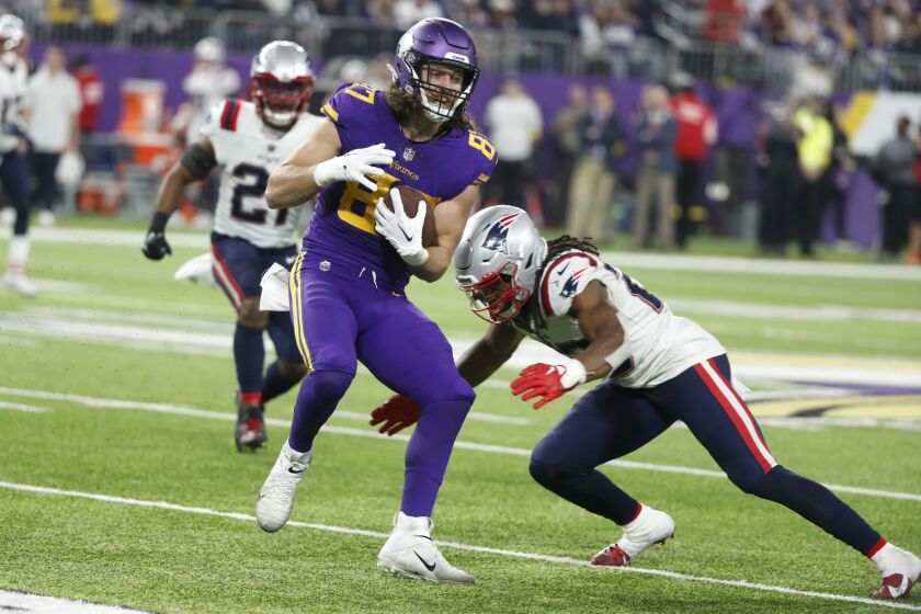 Minnesota Vikings tight end T.J. Hockenson (87) is tackled by New England Patriots safety Kyle Dugger, right, after catching a pass during the second half of an NFL football game, Thursday, Nov. 24, 2022, in Minneapolis. (AP Photo/Bruce Kluckhohn)