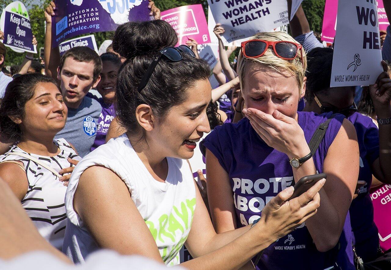 Abortion rights activists Morgan Hopkins of Boston, left, and Alison Turkos of New York City get the word on the steps of the United States Supreme Court that, in a 5-3 decision, the Court struck down a Texas law seen as one of the nation's toughest restrictions on abortion.