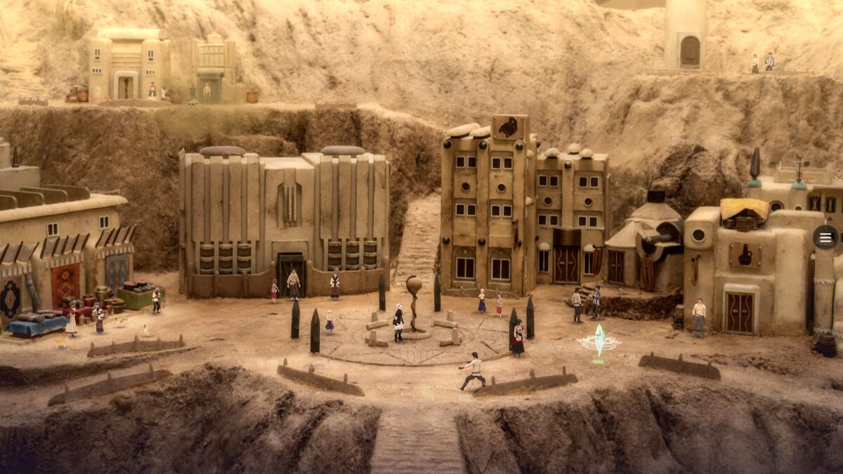 A diorama with miniature buildings and figures in a desert-type setting.
