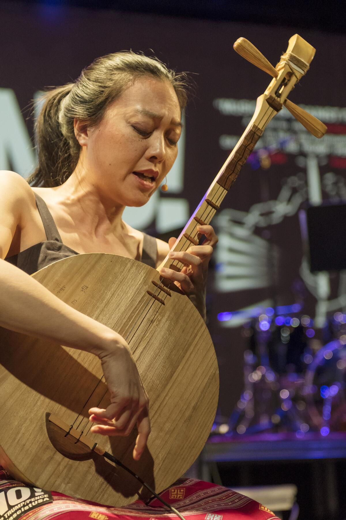Jen Shyu is shown playing a ruan, a Taiwanese moon lute.