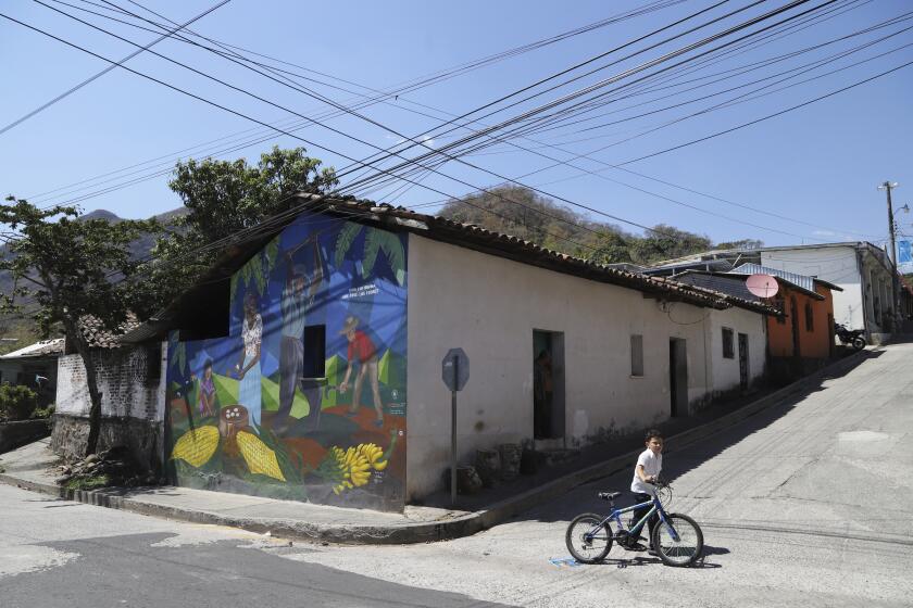 Un niño empuja su bicicleta junto a un mural que muestra campesinos y el mensaje "Vida cotidiana", en San José Las Flores, El Salvador, el miércoles 28 de febrero de 2024. El Salvador celebró sus elecciones municipales el 3 de marzo. (AP Foto/Salvador Meléndez)