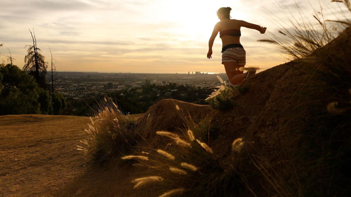 A woman runs in Griffith Park at sunset on Monday when the temperature was above 80 degrees.