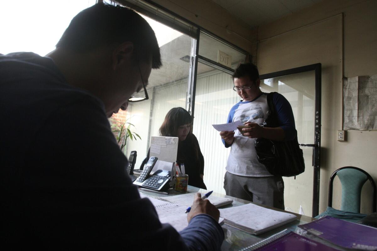 Genxiang Qin (left), 52, assists a couple from northeast China at Xing Xing Employment Agency on January 27, in Monterey Park. The agency assisted the couple, who are from Liaoning, China and did not wish to give their names, in getting a job at a massage parlor in Phoenix. Genxing Qin helps Chinese immigrants find jobs at small businesses around the country. Xing Xing is one of at least a dozen employment agencies at the interesection of Garfield and Garvey Avenues in Monterey Park.